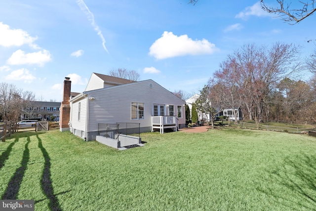 back of property with a yard, a chimney, and fence