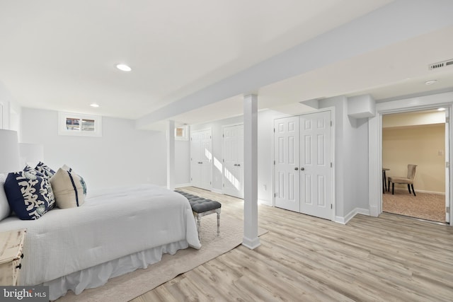 bedroom featuring visible vents, two closets, baseboards, light wood-type flooring, and recessed lighting