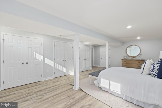 bedroom featuring visible vents, multiple closets, wood finished floors, recessed lighting, and baseboards