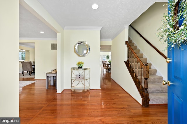 entrance foyer with visible vents, stairs, and wood finished floors