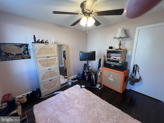 interior space featuring dark wood-type flooring, a ceiling fan, and baseboards