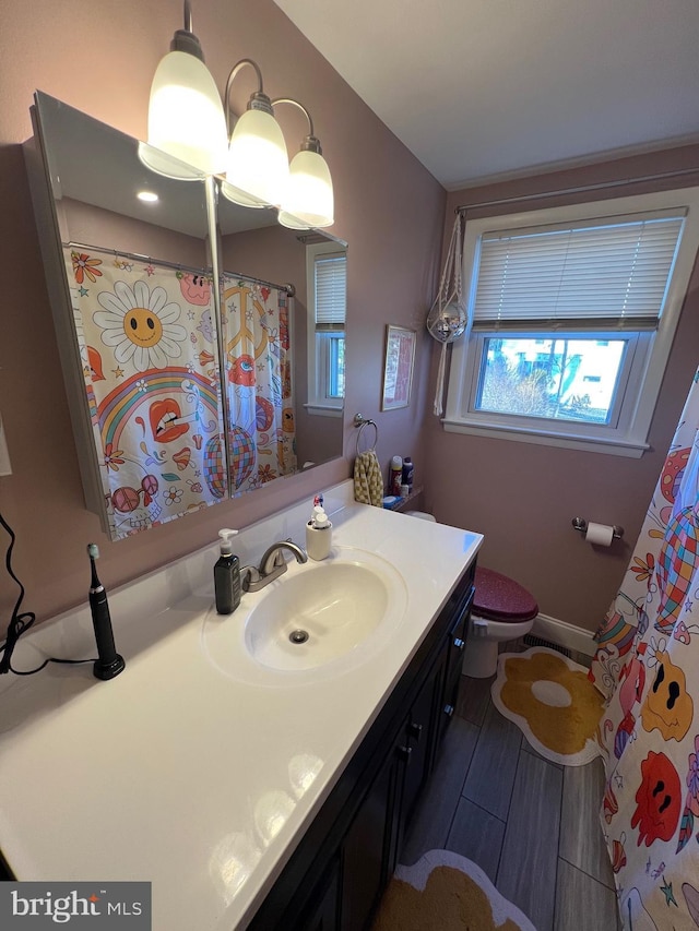 bathroom with toilet, vanity, and baseboards