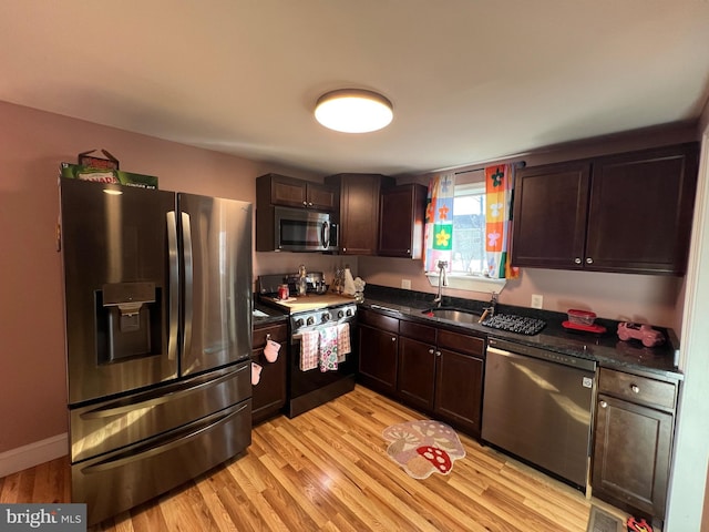 kitchen featuring dark brown cabinetry, light wood-style flooring, appliances with stainless steel finishes, and a sink