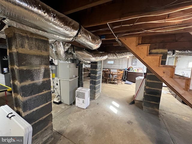 unfinished basement with gas water heater, heating unit, electric panel, and stairs