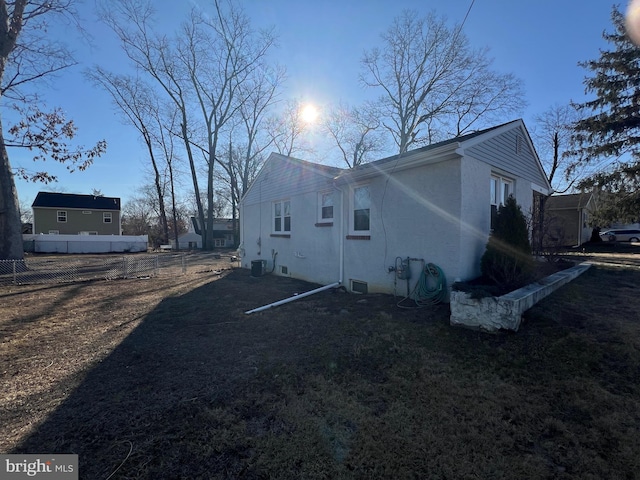 view of side of property with stucco siding, cooling unit, and fence