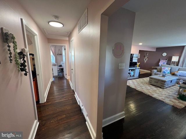 hallway featuring visible vents, baseboards, and dark wood finished floors