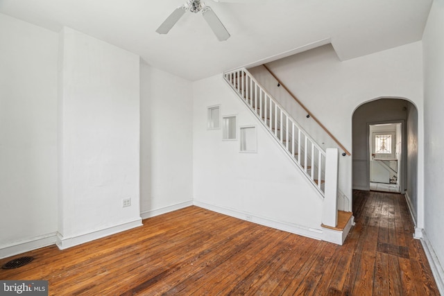 interior space with hardwood / wood-style flooring, stairway, a ceiling fan, and arched walkways