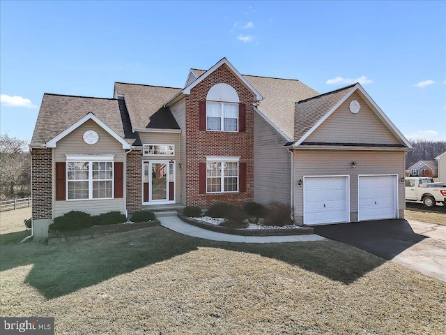 traditional-style house featuring a front yard, an attached garage, brick siding, and driveway