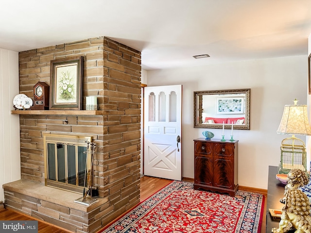 interior space featuring baseboards, a large fireplace, and wood finished floors