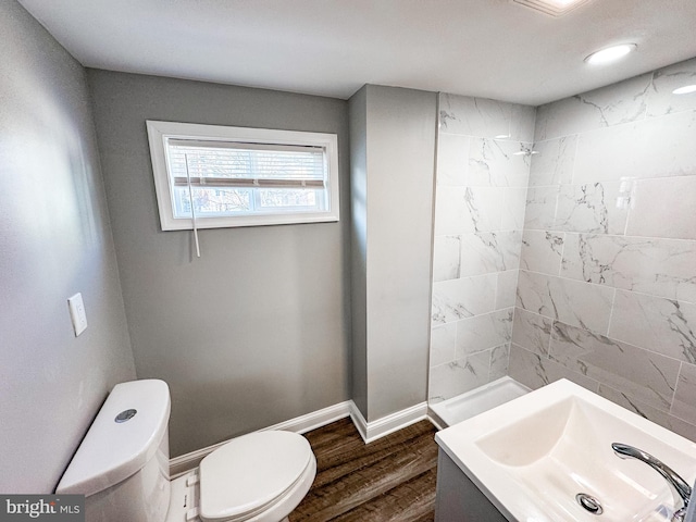 bathroom with tiled shower, baseboards, toilet, and wood finished floors