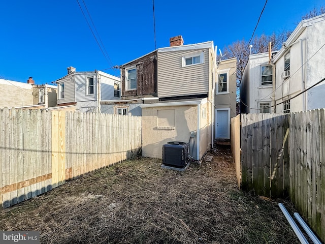 rear view of house with a residential view, central AC unit, a chimney, and fence