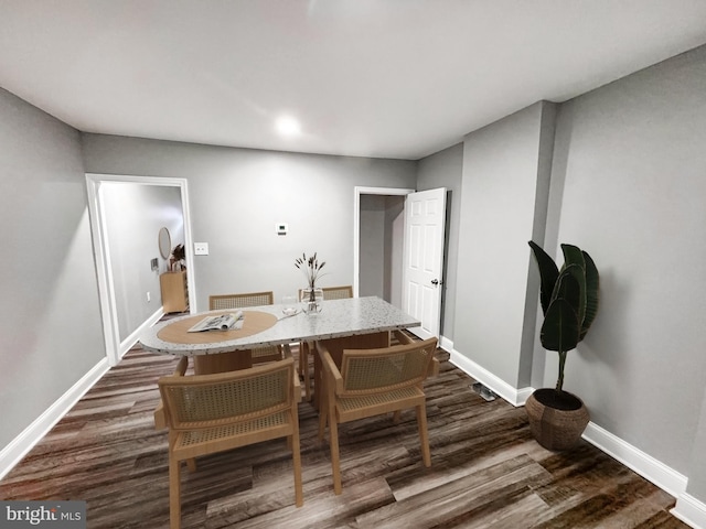 dining space featuring dark wood-type flooring and baseboards