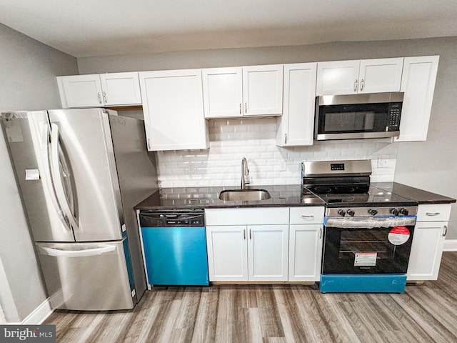 kitchen with white cabinets, light wood-style flooring, appliances with stainless steel finishes, and a sink