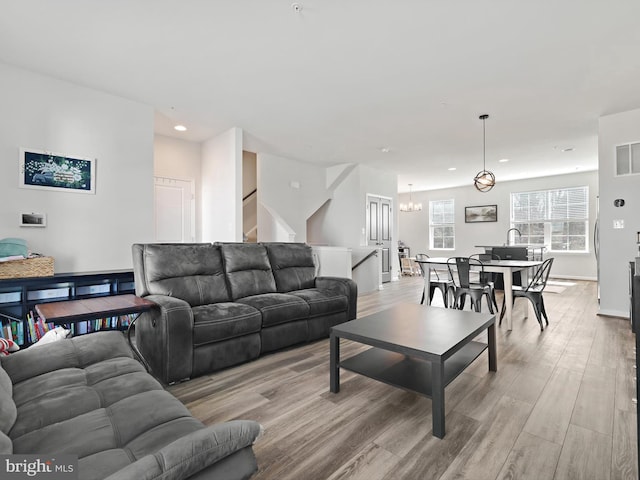 living room featuring visible vents, a notable chandelier, light wood-style flooring, recessed lighting, and stairway