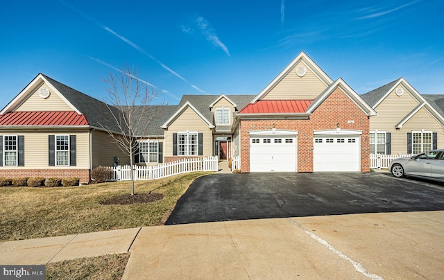 view of front of home featuring fence, a standing seam roof, an attached garage, brick siding, and metal roof