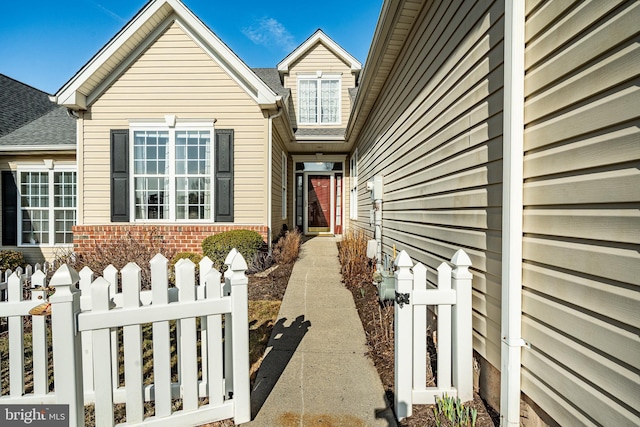 view of exterior entry featuring fence and brick siding