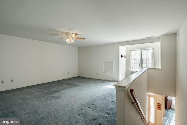 empty room with visible vents, carpet floors, baseboards, and ceiling fan