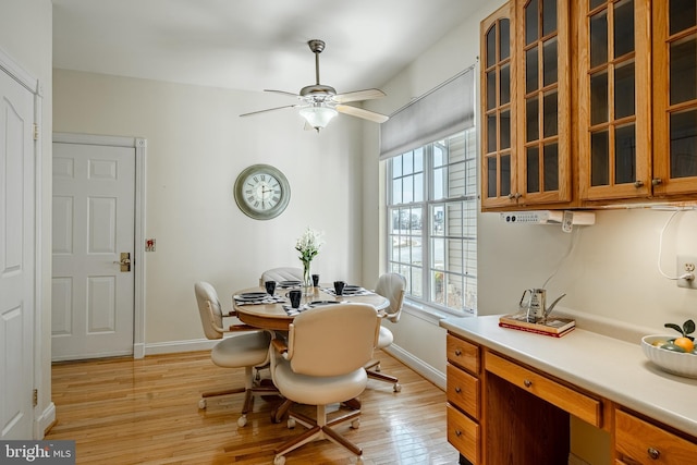 dining room featuring a ceiling fan, baseboards, and light wood finished floors