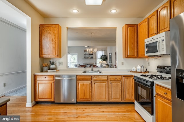 kitchen featuring a sink, light wood-style floors, appliances with stainless steel finishes, and light countertops