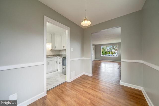 unfurnished dining area featuring visible vents, baseboards, and light wood-style floors