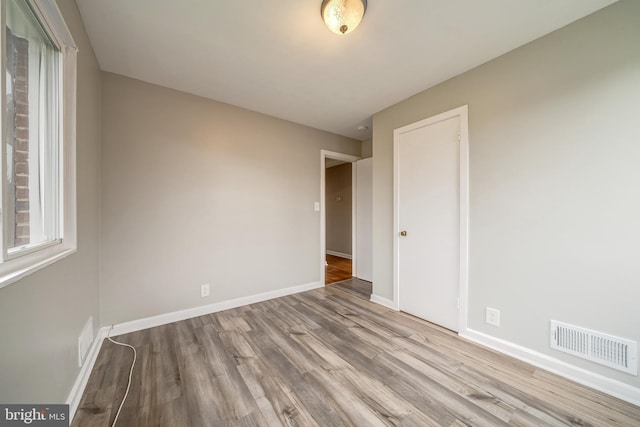 empty room featuring wood finished floors, visible vents, and baseboards