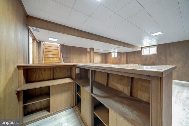 interior space with stairs, wooden walls, wood finished floors, and a dry bar