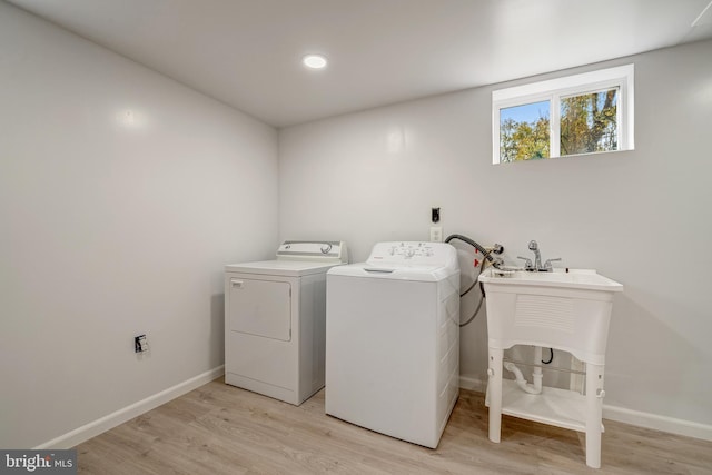 clothes washing area featuring light wood-style flooring, baseboards, washing machine and dryer, and laundry area