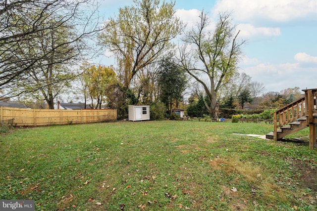 view of yard featuring an outbuilding, a shed, stairway, and fence