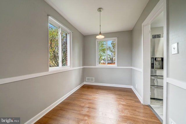 unfurnished dining area with visible vents, light wood-style floors, and a healthy amount of sunlight