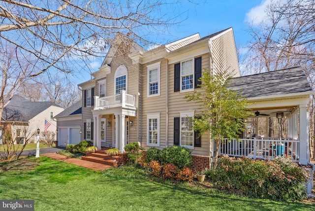 view of front facade featuring a porch, a front yard, a garage, a balcony, and ceiling fan