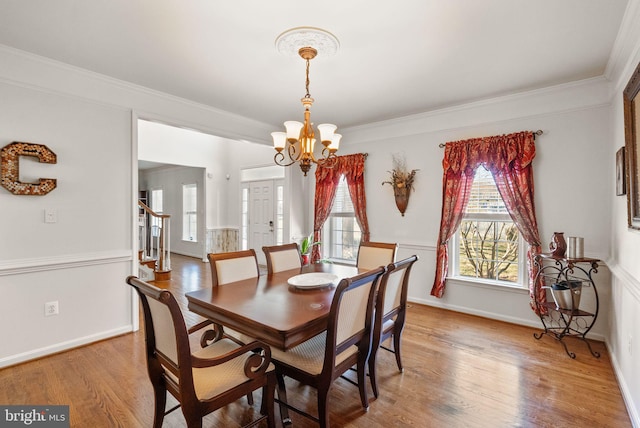 dining space with crown molding, baseboards, stairway, light wood-style flooring, and an inviting chandelier