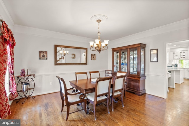 dining area with baseboards, a notable chandelier, wood finished floors, and ornamental molding