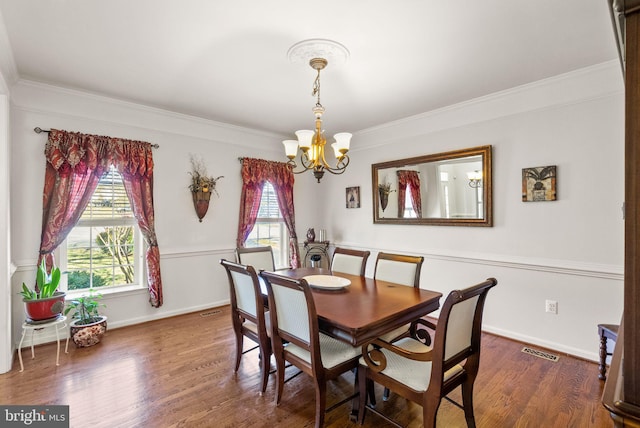 dining room featuring visible vents, a notable chandelier, wood finished floors, and crown molding