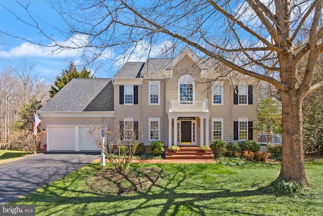 view of front of home featuring a balcony, roof with shingles, an attached garage, a front lawn, and aphalt driveway