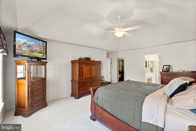 bedroom with light colored carpet, ensuite bathroom, a walk in closet, and vaulted ceiling