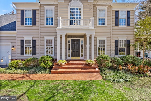 view of front of property featuring a balcony, a garage, and a shingled roof