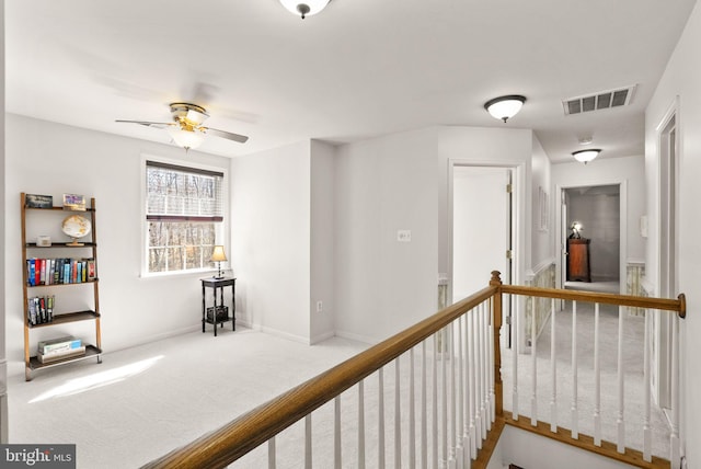 corridor featuring baseboards, visible vents, an upstairs landing, and carpet floors