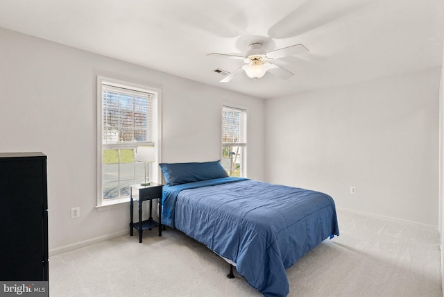 bedroom featuring visible vents, baseboards, light colored carpet, and a ceiling fan