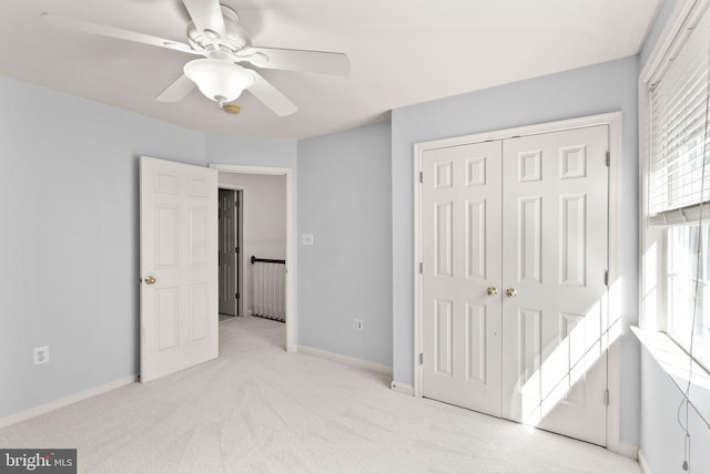 unfurnished bedroom with a closet, light carpet, baseboards, and a ceiling fan