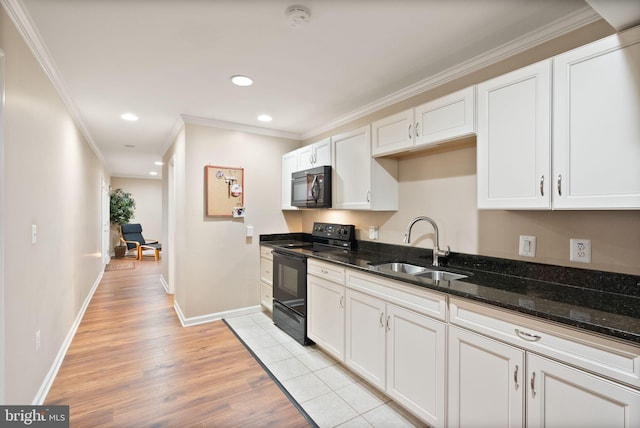 kitchen featuring black appliances, dark stone counters, light wood-type flooring, white cabinetry, and a sink