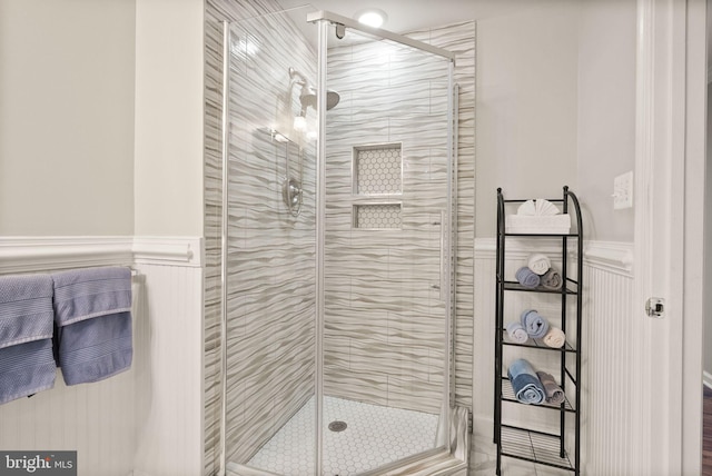 full bathroom featuring a stall shower and wainscoting