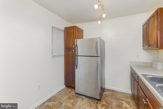 8500 Laguna Ct Unit 218, Alexandria, VA 22309 - kitchen with freestanding refrigerator, brown cabinetry, baseboards, and light countertops