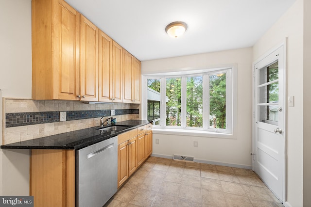 kitchen featuring stainless steel dishwasher, a sink, decorative backsplash, baseboards, and dark stone counters