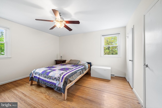 bedroom featuring multiple windows, light wood finished floors, and baseboards