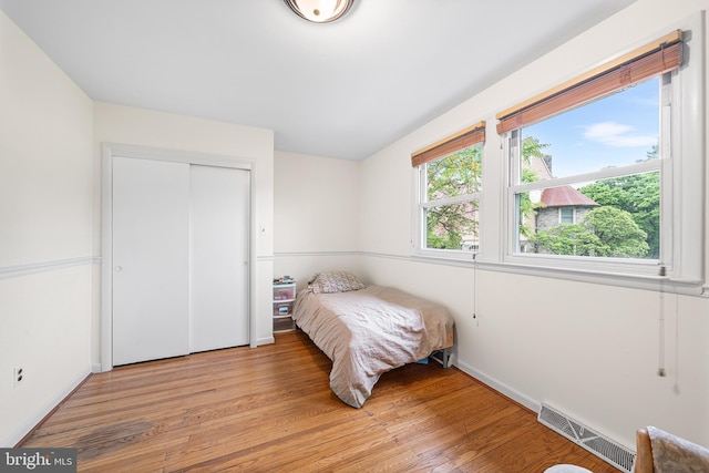 bedroom featuring light wood-type flooring, a closet, and baseboards