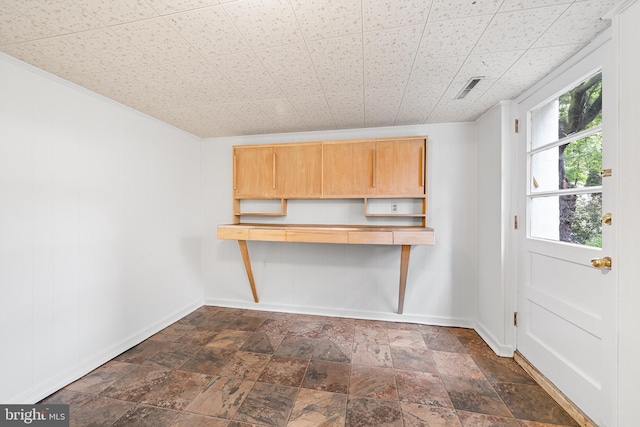 unfurnished dining area featuring baseboards and dark stone finish flooring