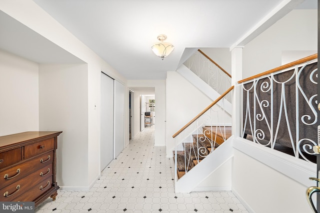 hall featuring light flooring, stairs, and baseboards