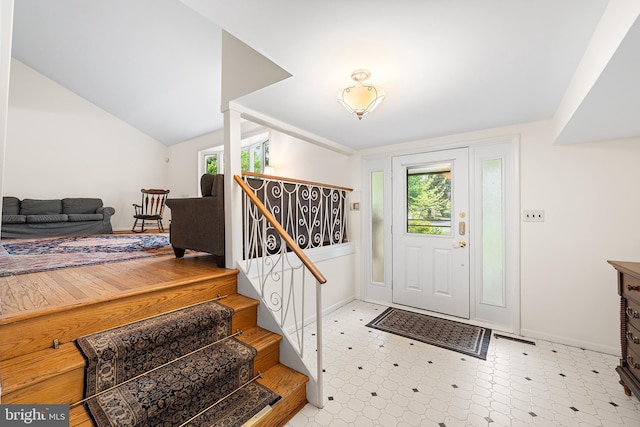 entryway featuring tile patterned floors, baseboards, stairs, and lofted ceiling