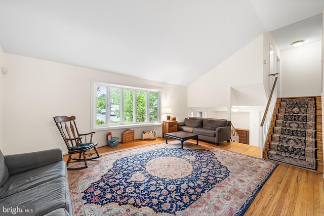 living area featuring wood finished floors, stairway, and high vaulted ceiling