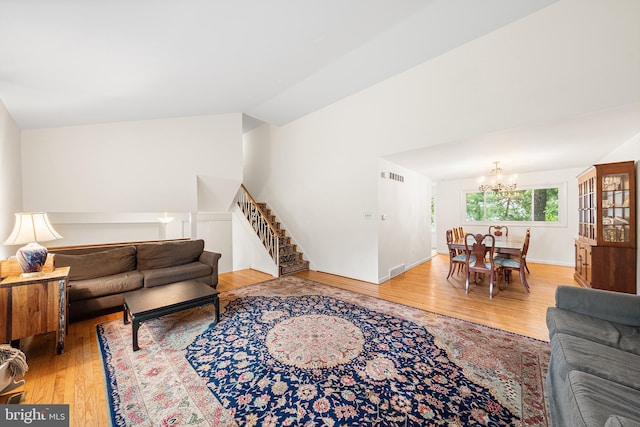 living room with a chandelier, wood finished floors, vaulted ceiling, and stairs